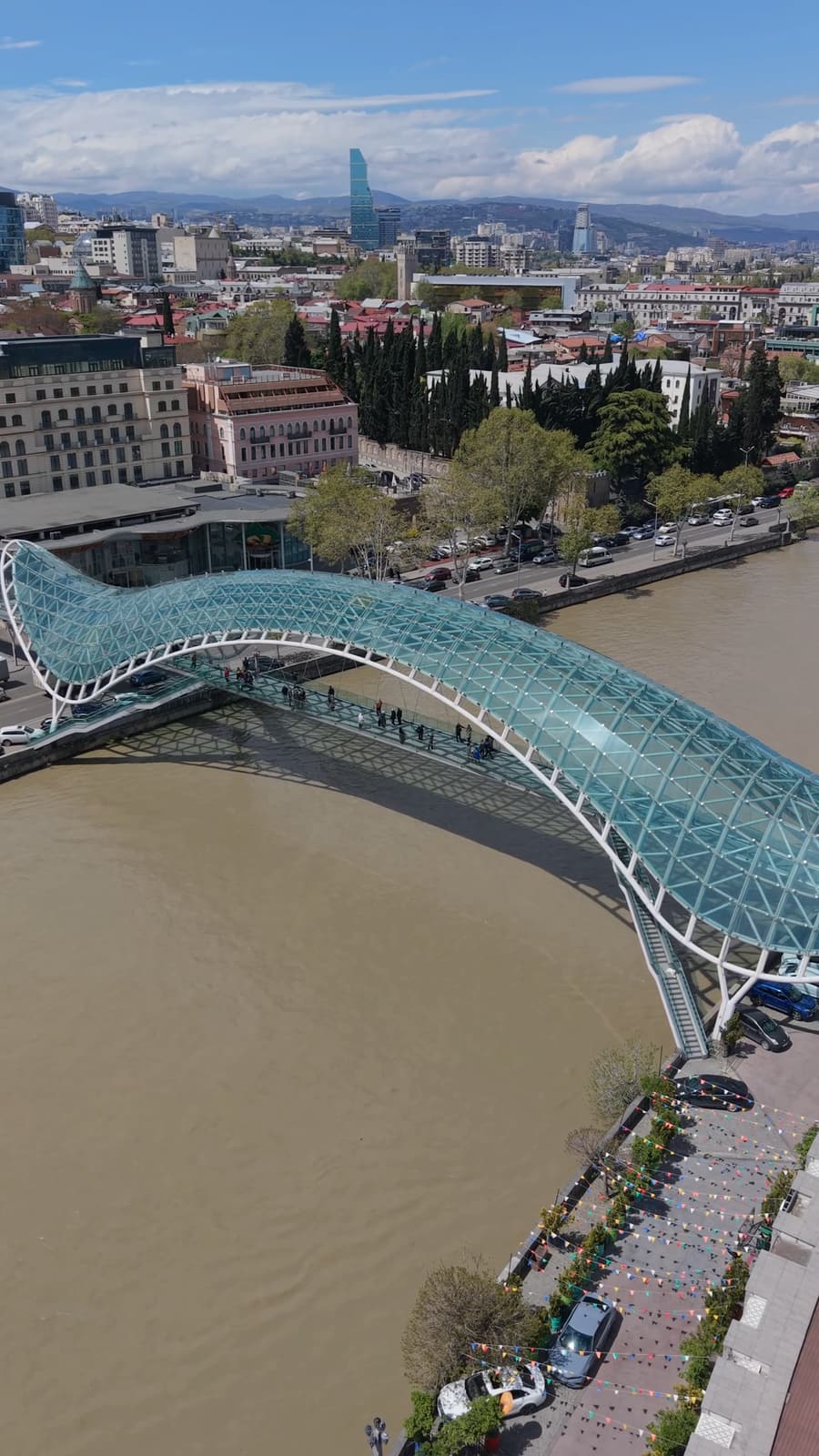 Стеклянный Мост Мира через реку Куру в Тбилиси, на фоне города